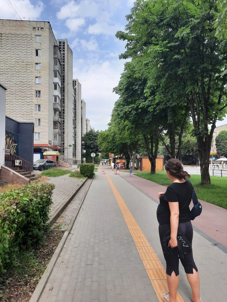 Voie piétonnière et piste cyclable, séparées de la rue par une bande de verdure, et qui longent le quartier résidentiel.